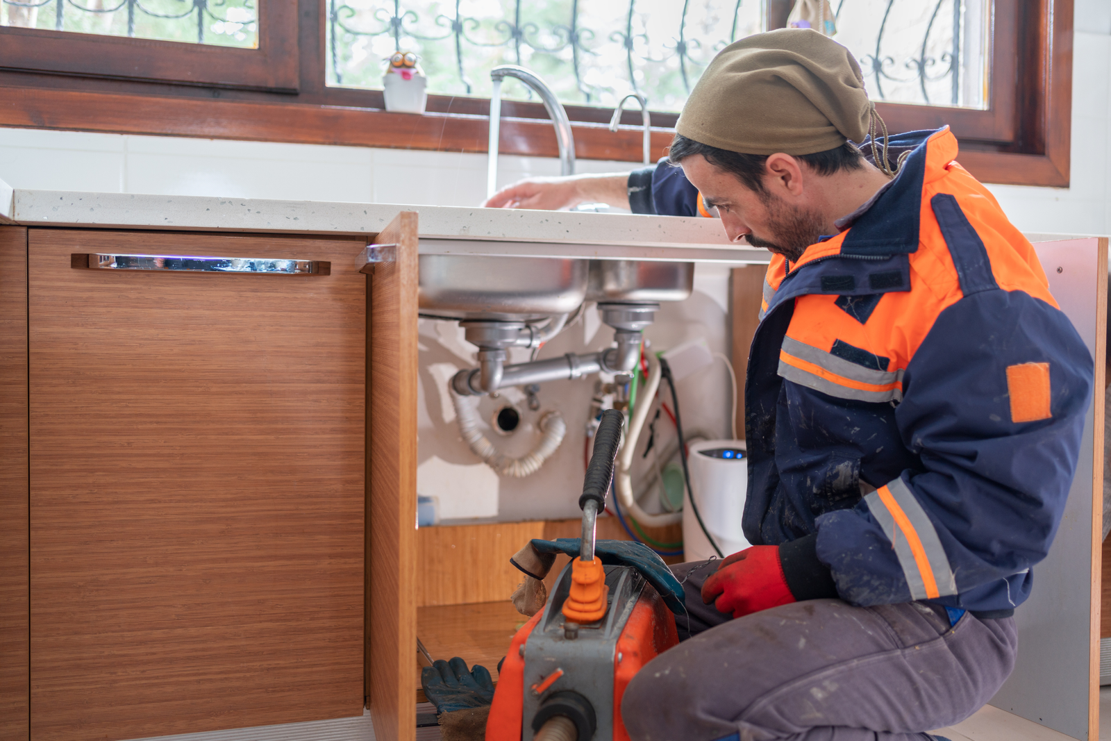 Plumber cleaning and fixing a clogged drain.